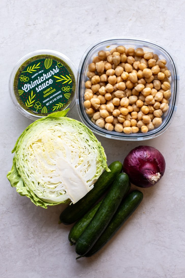 Ingredient photo with Trader Joe's Chimichurri Sauce, cooked chickpeas, cabbage, red onion, and Persian cucumbers.